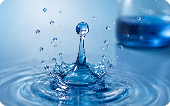 Close-up of a water droplet creating ripples on a blue background